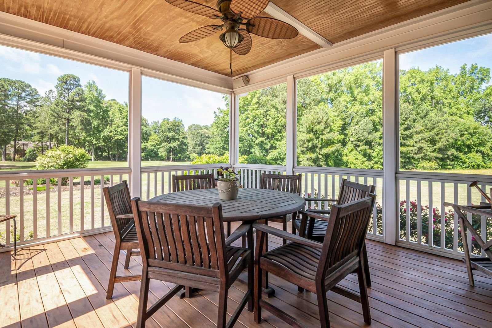 Screened patio enclosure with a dining set overlooking a lawn