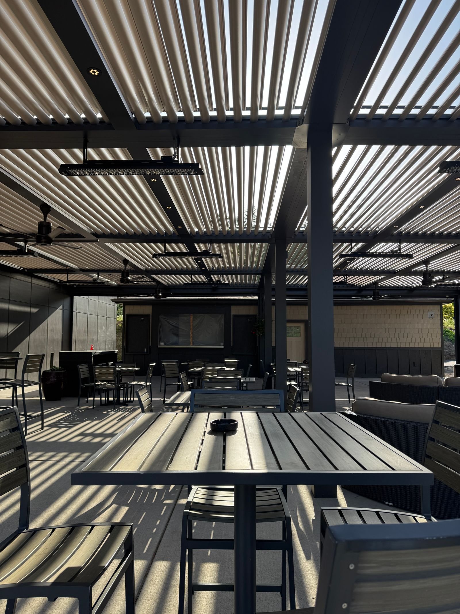 Adjustable metal louvre roof over an outdoor seating area