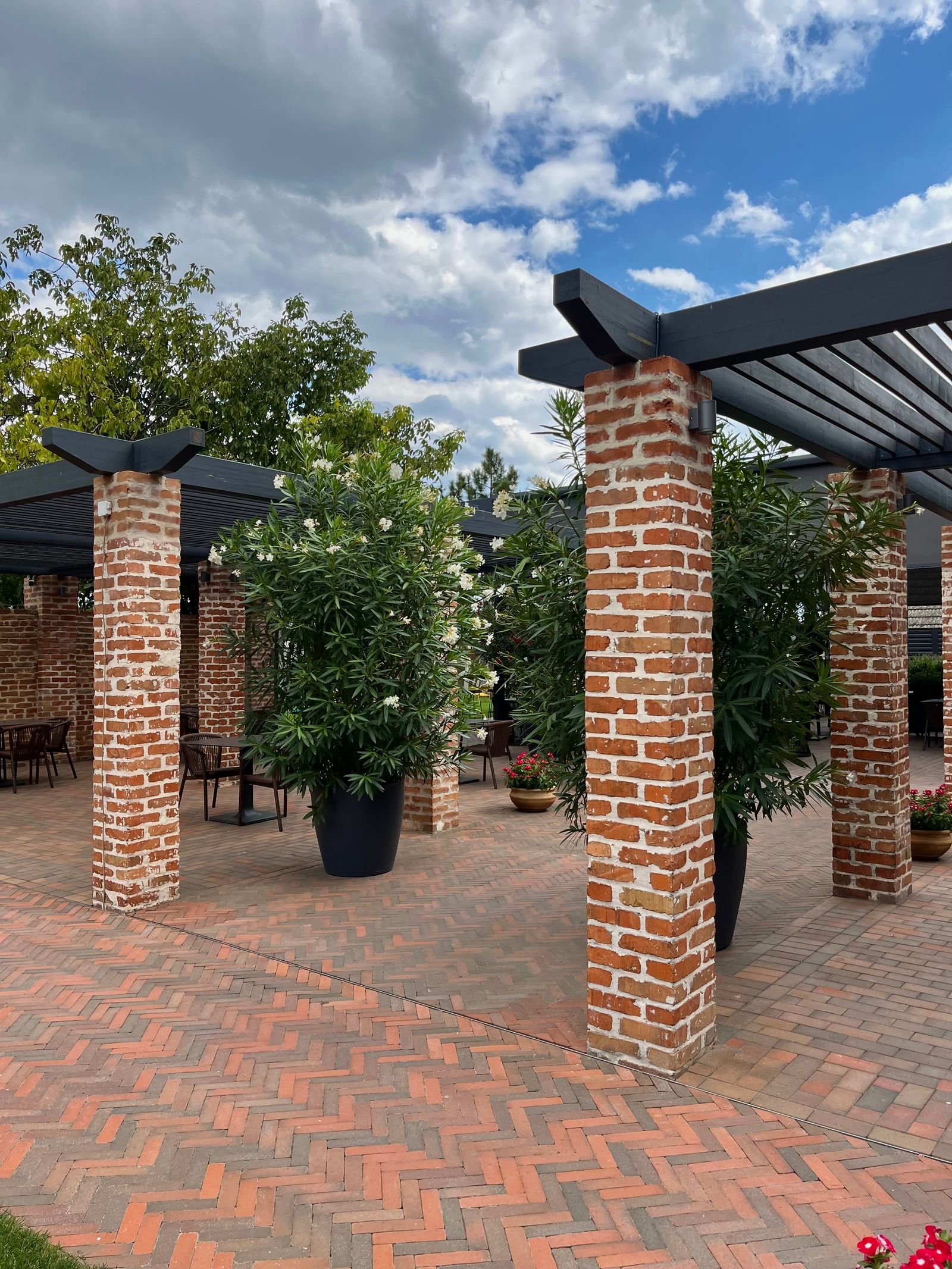 Brick columns supporting a slatted pergola over a paved terrace